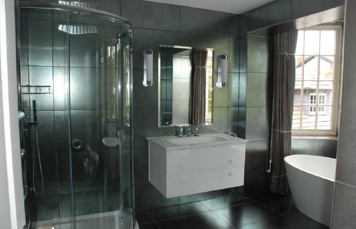 A view of the bath, sink and shower cubicle in a black tiled ensuite bathroom.