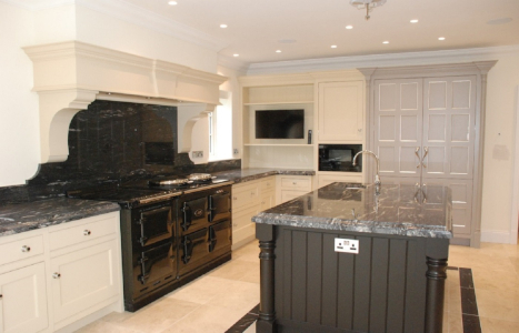 Kitchen with black marble worktops, white cabinets and a single black island.