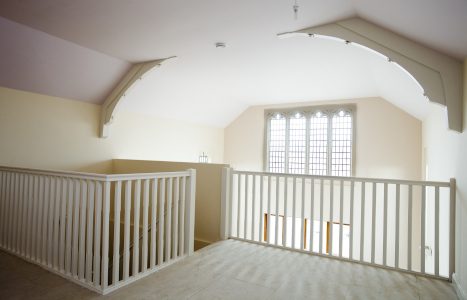 Landing view of a staircase with white banisters, in a windowed room.